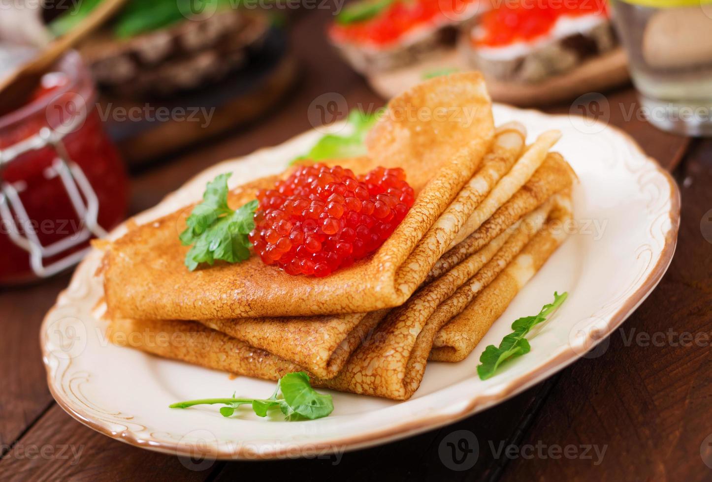 Pancakes with red caviar on plate. Russian cuisine. Maslenitsa photo