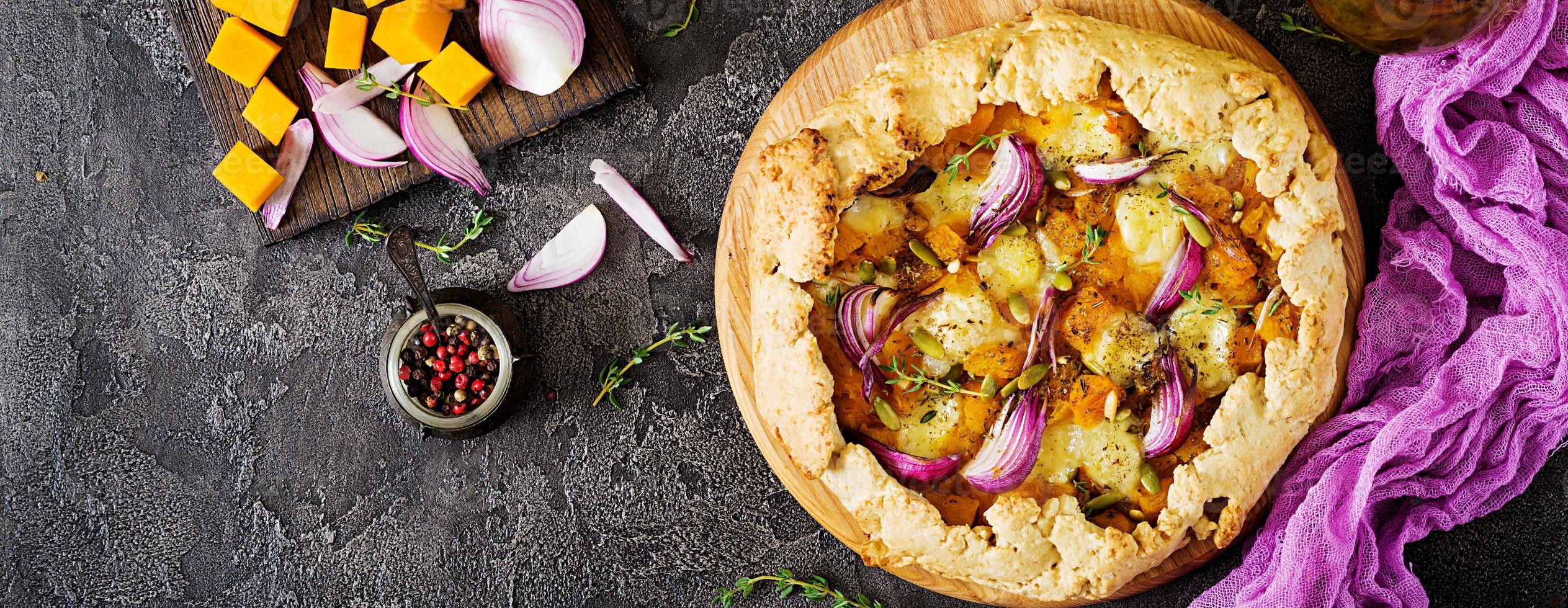 Galette pie with pumpkin and mozzarella cheese on dark background. Thanksgiving day food. Banner. Top view. photo