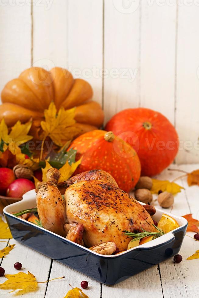 pavo asado adornado con arándanos sobre una mesa de estilo rústico decorada con calabazas, naranjas, manzanas y hojas de otoño. día de Gracias. foto