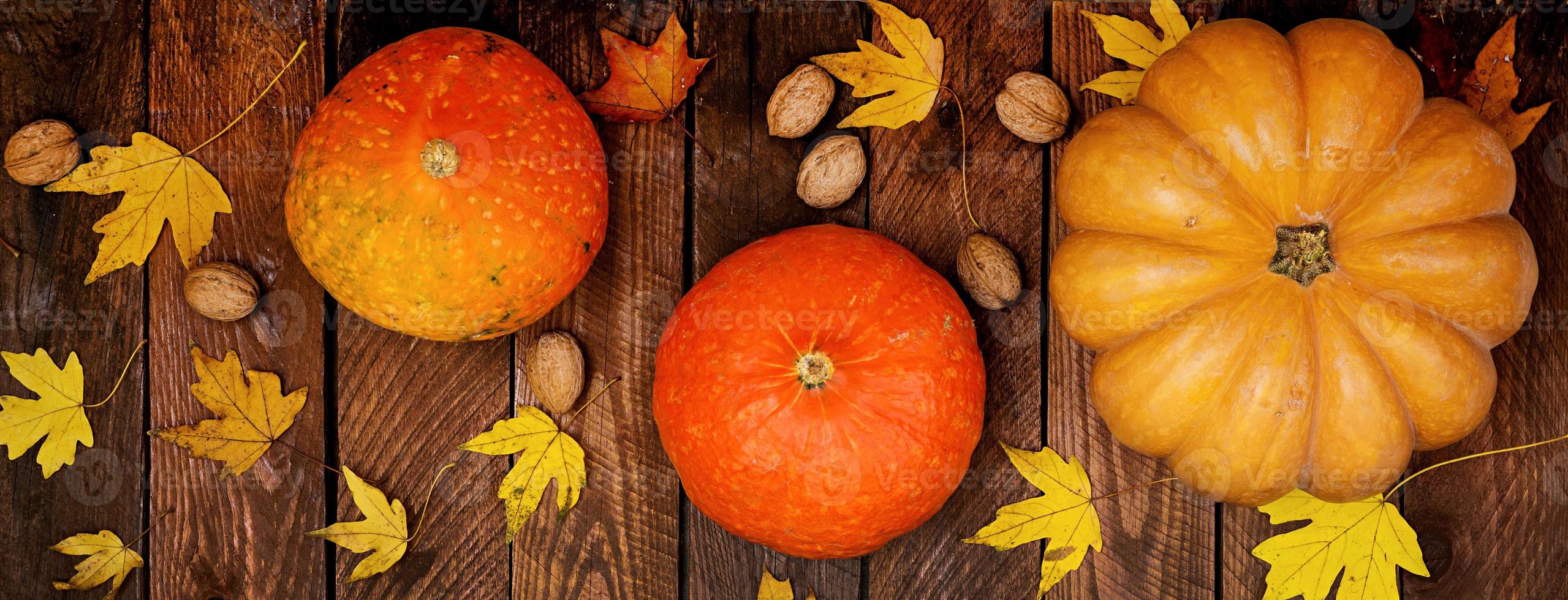 Thanksgiving background. Pumpkins and fallen leaves on white wooden background.  Halloween or Thanksgiving day or seasonal autumnal.  Flat lay. Top view. Banner photo