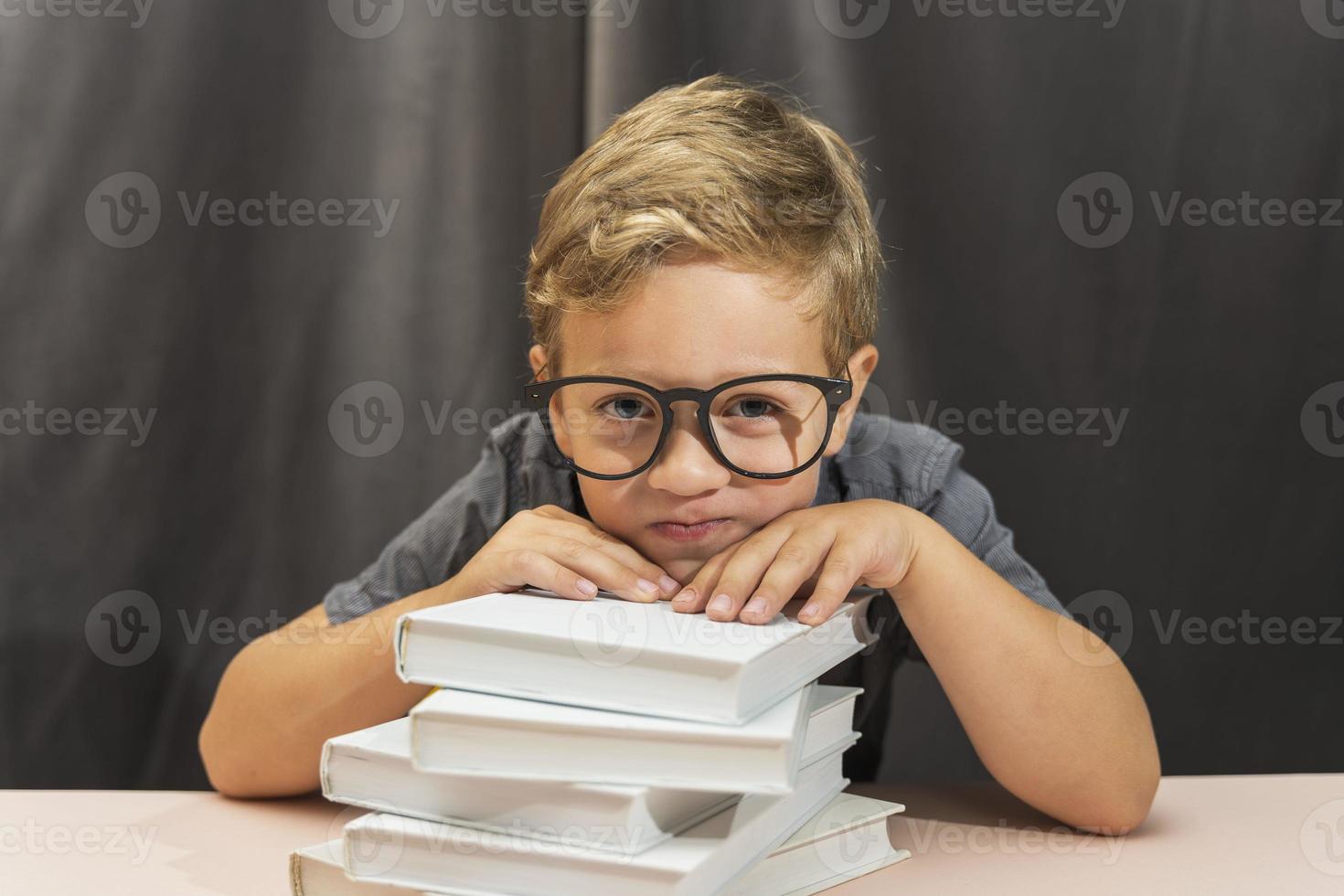 a boy with glasses and a stack of books, back to school, study fatigue, study difficulties photo