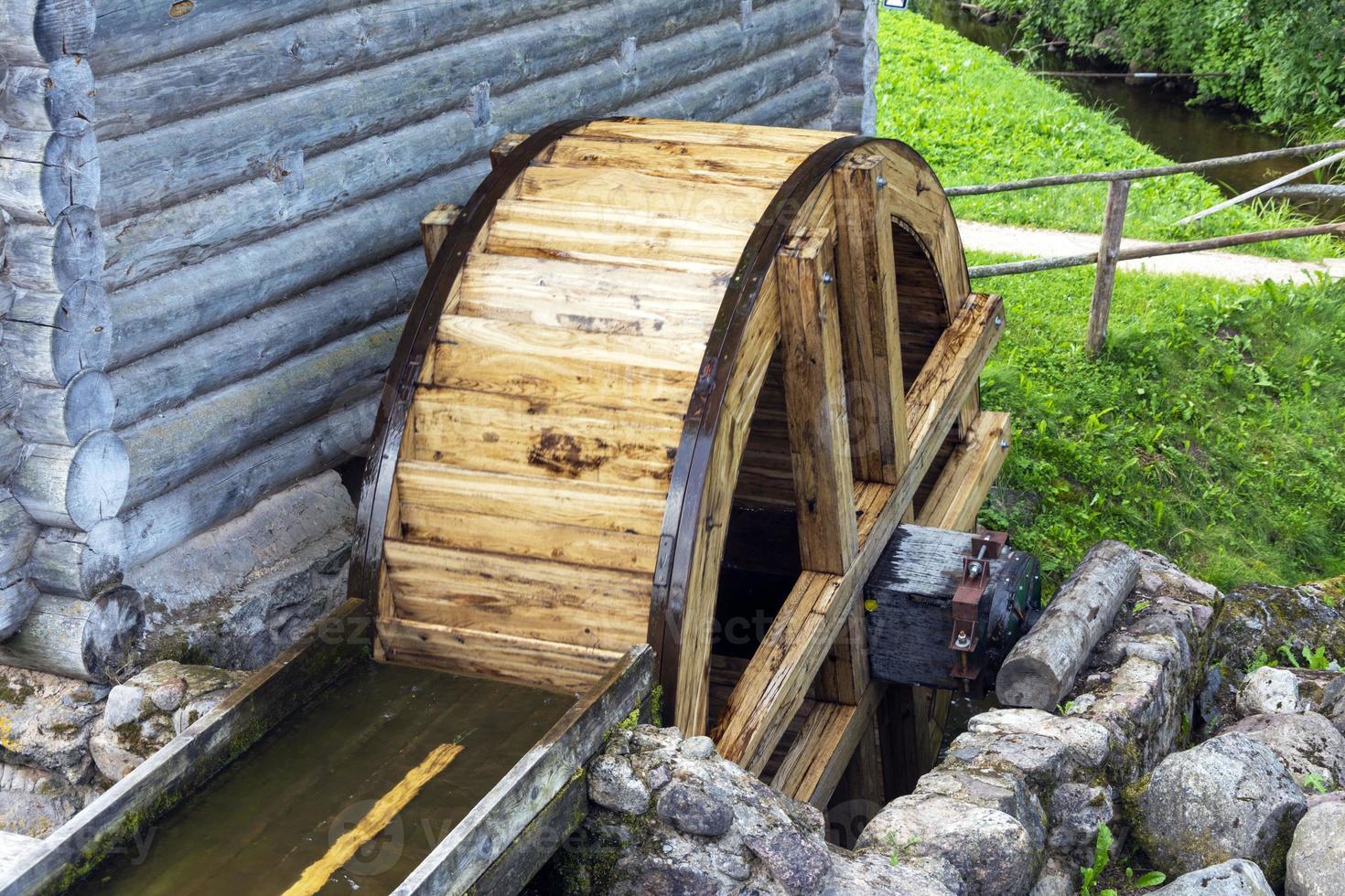 The wheel of an old water mill. A village mill, the wheel of which rotates under the influence of the force of water photo
