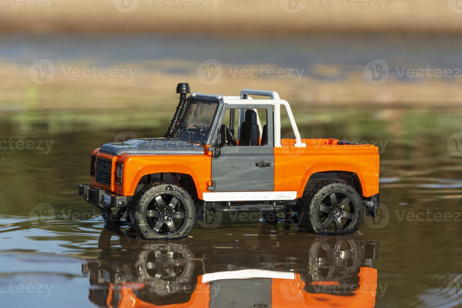 Toy off-road car among sand and water in nature photo