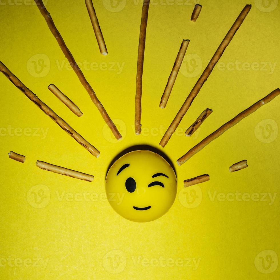 A creative composition of a smiley face and rays of light from it, a minimalistic concept, a sun on a yellow background photo