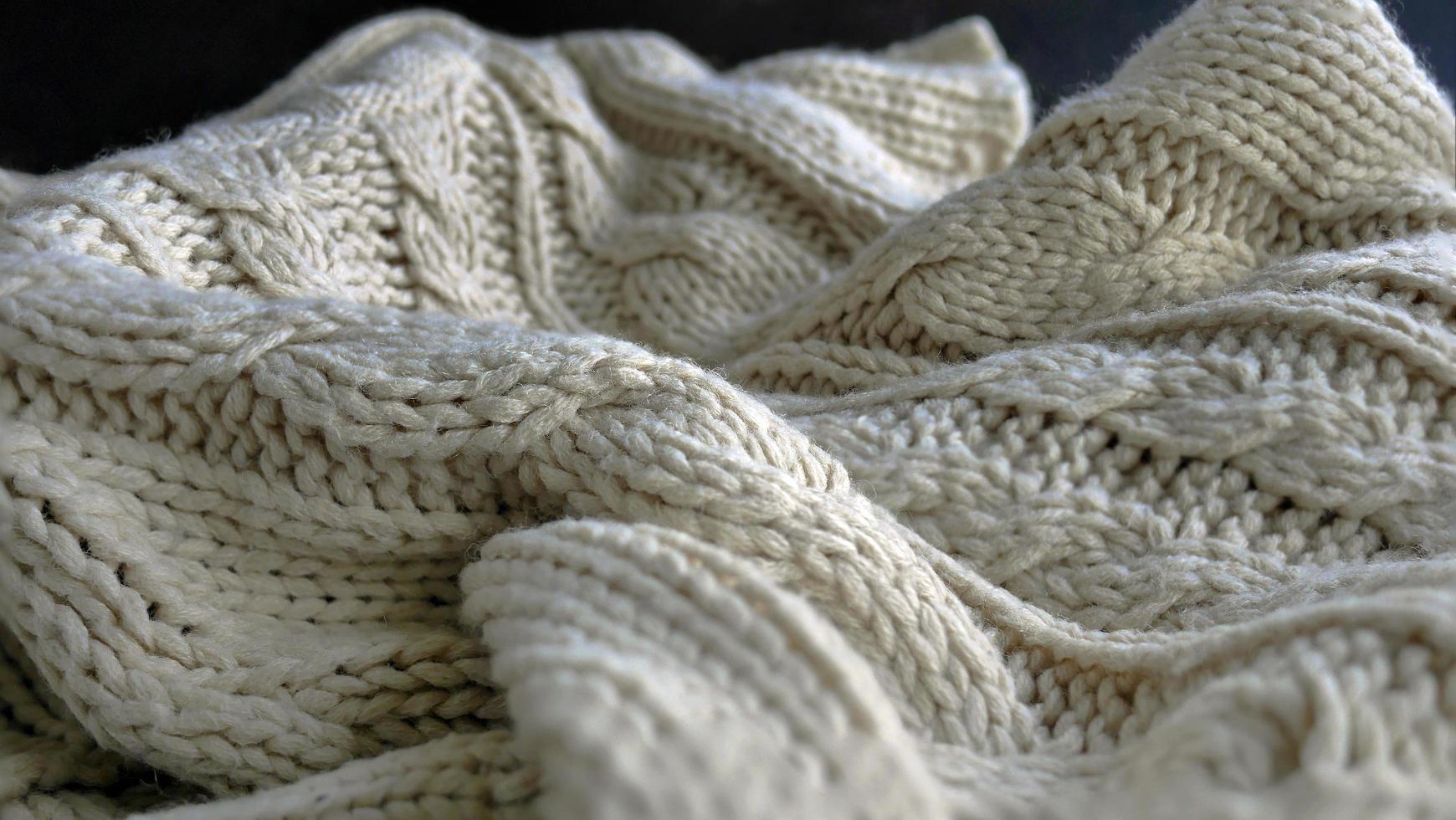 Selective focus Knitted Woolen, Knitwear Fabric Texture, Warm Clothes for Fall and Winter, Woven, Woolen, Sweaters, beige, cream color with Dark Background and copy space photo