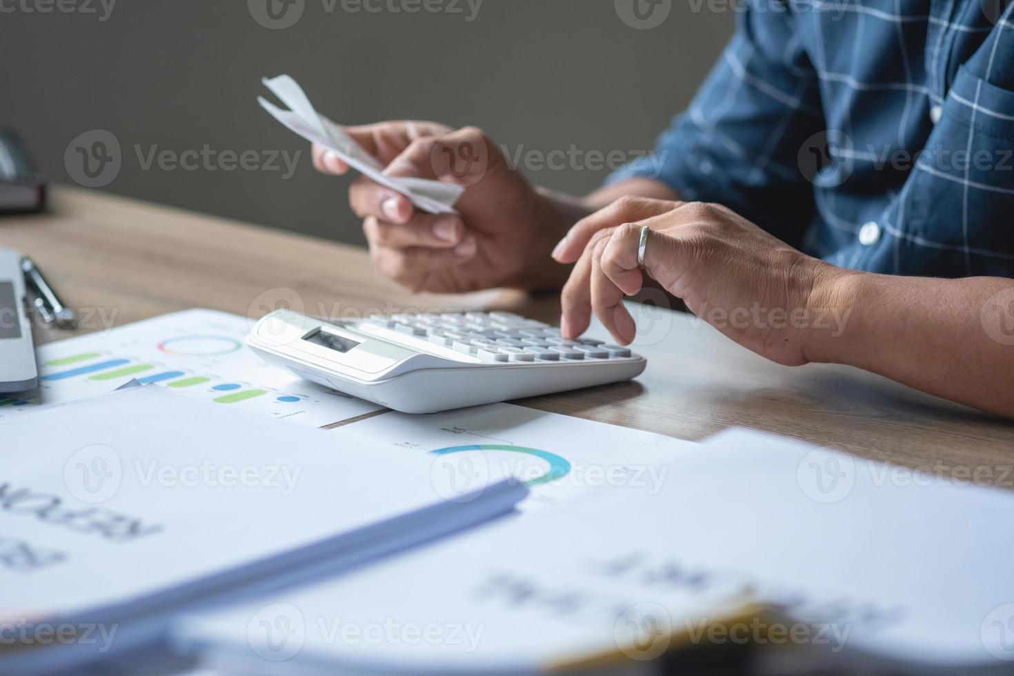 Marketing, Financial, Accounting, Planning, Business man calculating company bills with a calculator on his desk. photo