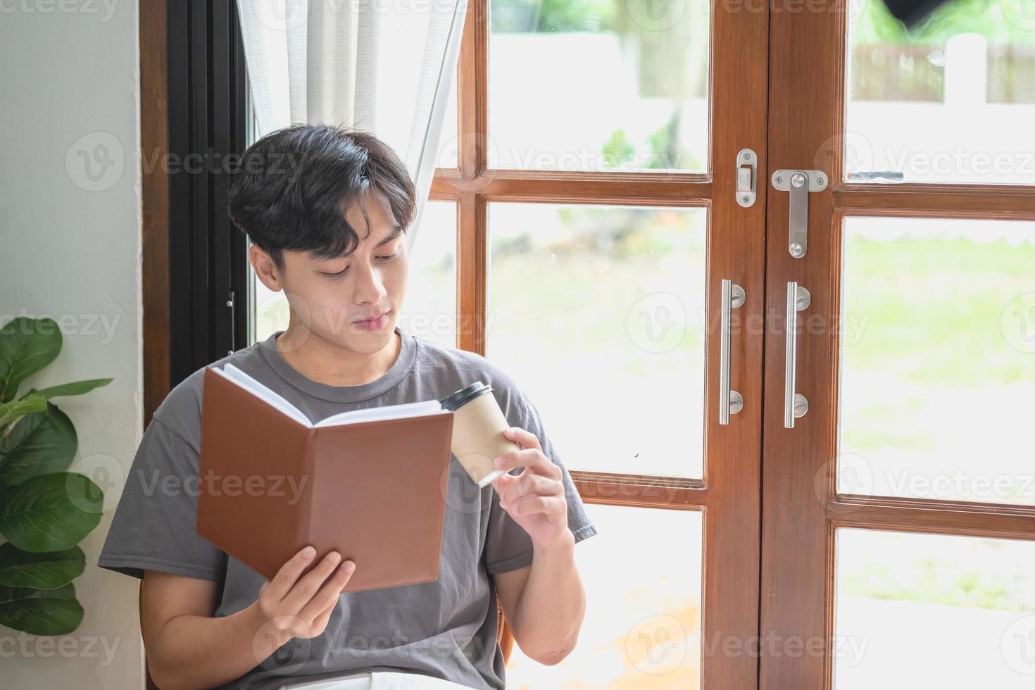 retrato de un hombre blanco sentado dentro de la casa leyendo y tomando café para relajarse en vacaciones. foto