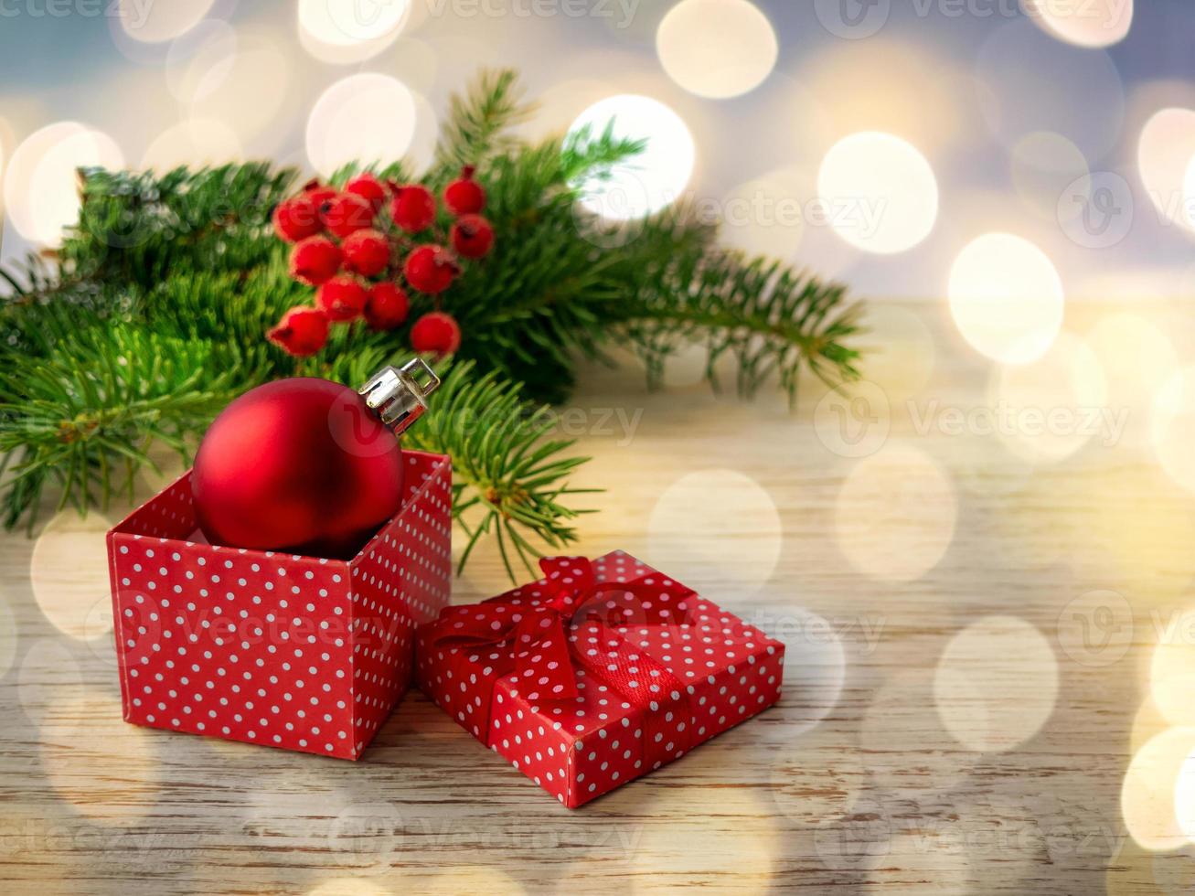 Red ball in a gift box on wooden background. Blurred background, bokeh. The concept of Christmas, New year. photo