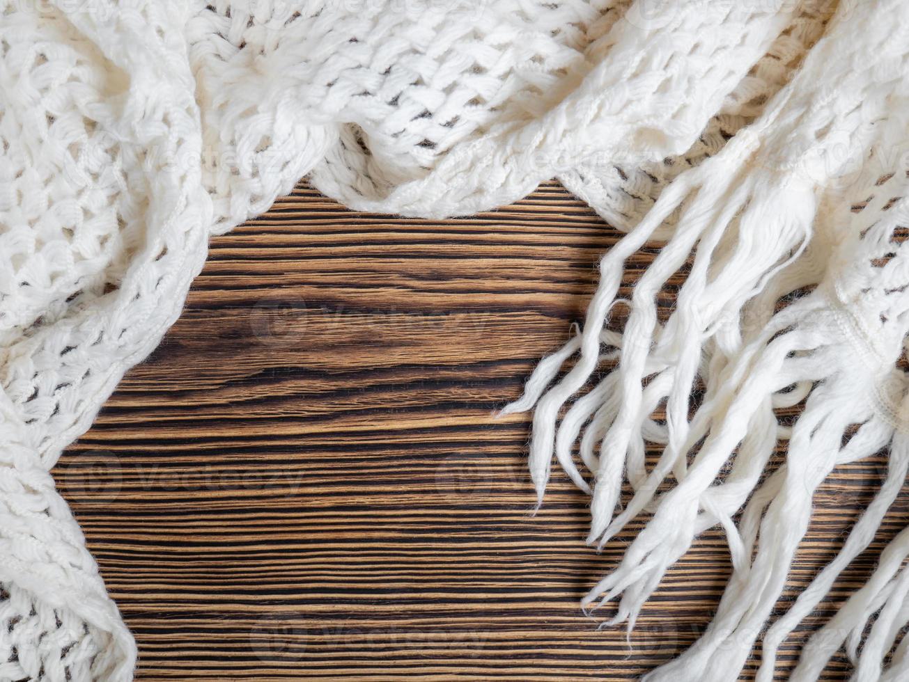 Warm cozy white scarf on a wooden background. Place for text photo