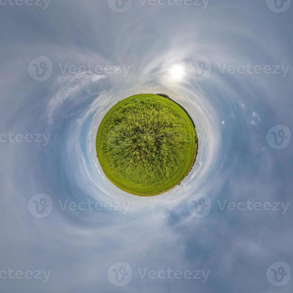 tiny planet in blue sky with beautiful clouds with transformation of spherical panorama 360 degrees. Spherical abstract aerial view. Curvature of space. photo