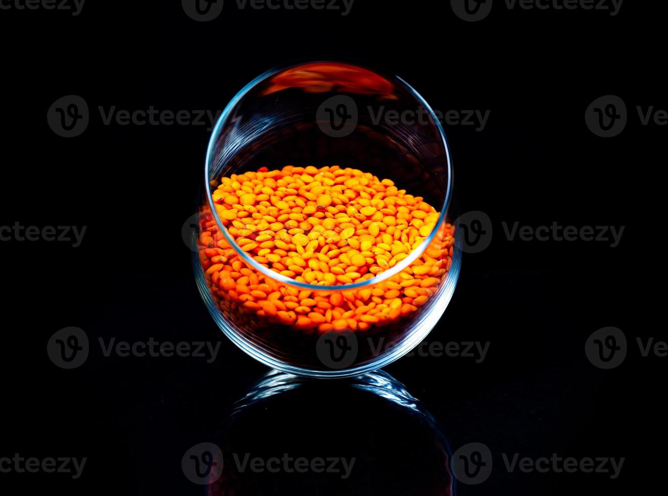 Close up of Raw Masur dal or masoor lentils or pink lentils in a black colored clay bowl on black in wineglass glass jar bucket photo