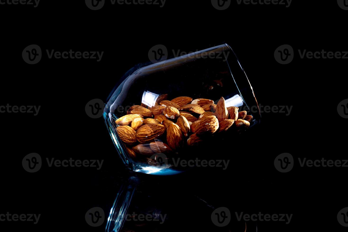 almendra pelada en un cubo de copa de vino sobre un fondo negro aislado. fila de tazones con nueces almendras, vista frontal. foto