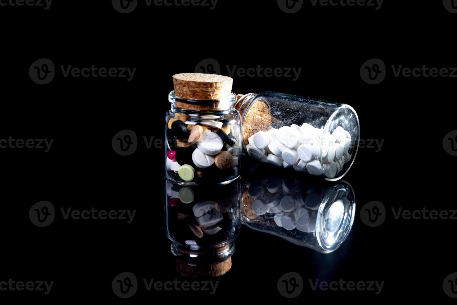 white orange pills in wineglass glass . in jar. in bucket Isolated on black set of capsule and pills inside closeup, photo