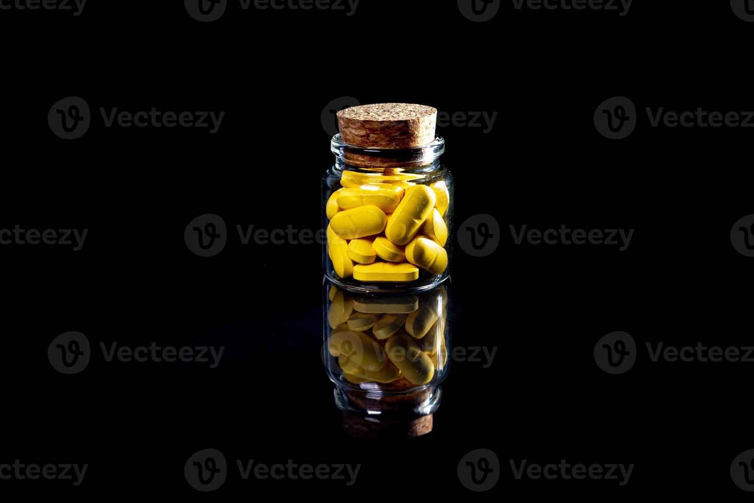 white orange pills in wineglass glass . in jar. in bucket Isolated on black set of capsule and pills inside closeup, photo