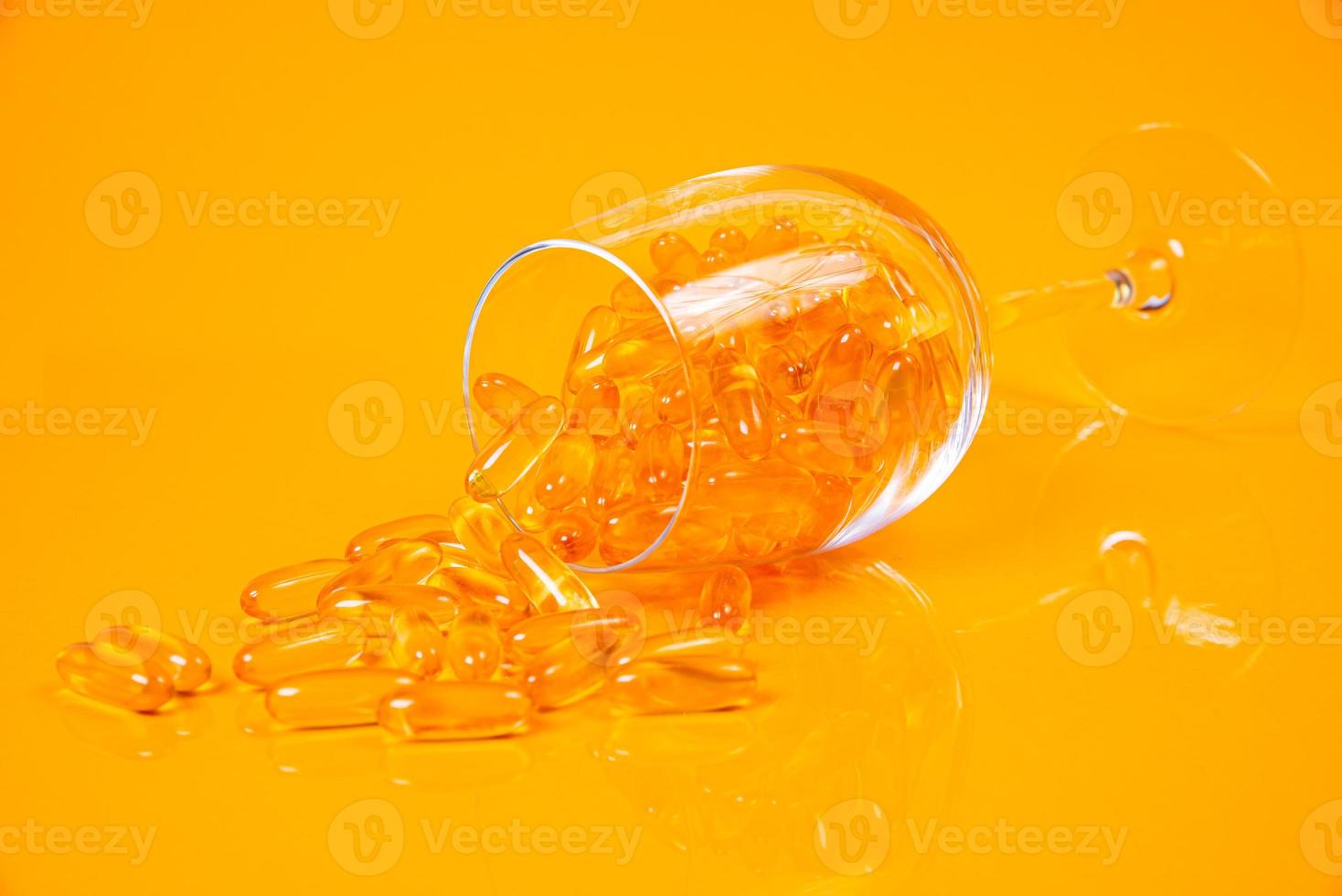 cápsulas de aceite de pescado. Píldoras amarillas de omega 3 en frasco en amarillo y naranja. cápsulas de aceite de pescado en vidrio. en tarro en ampollas cubo foto