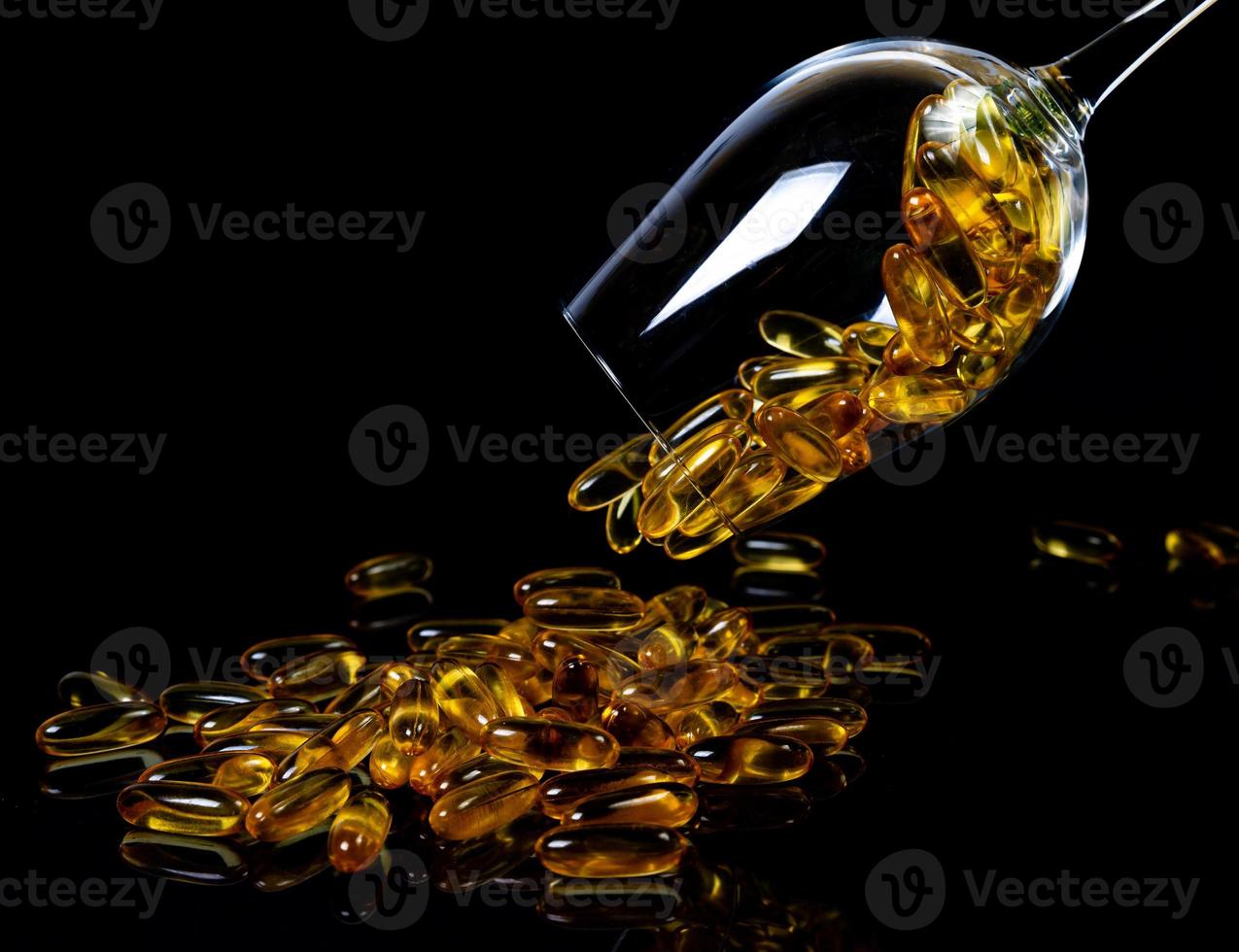 Fish oil capsules. Yellow omega 3 pills in jar on the dark black. fish oil capsules in wineglass glass . in jar. in bucket ampoules photo