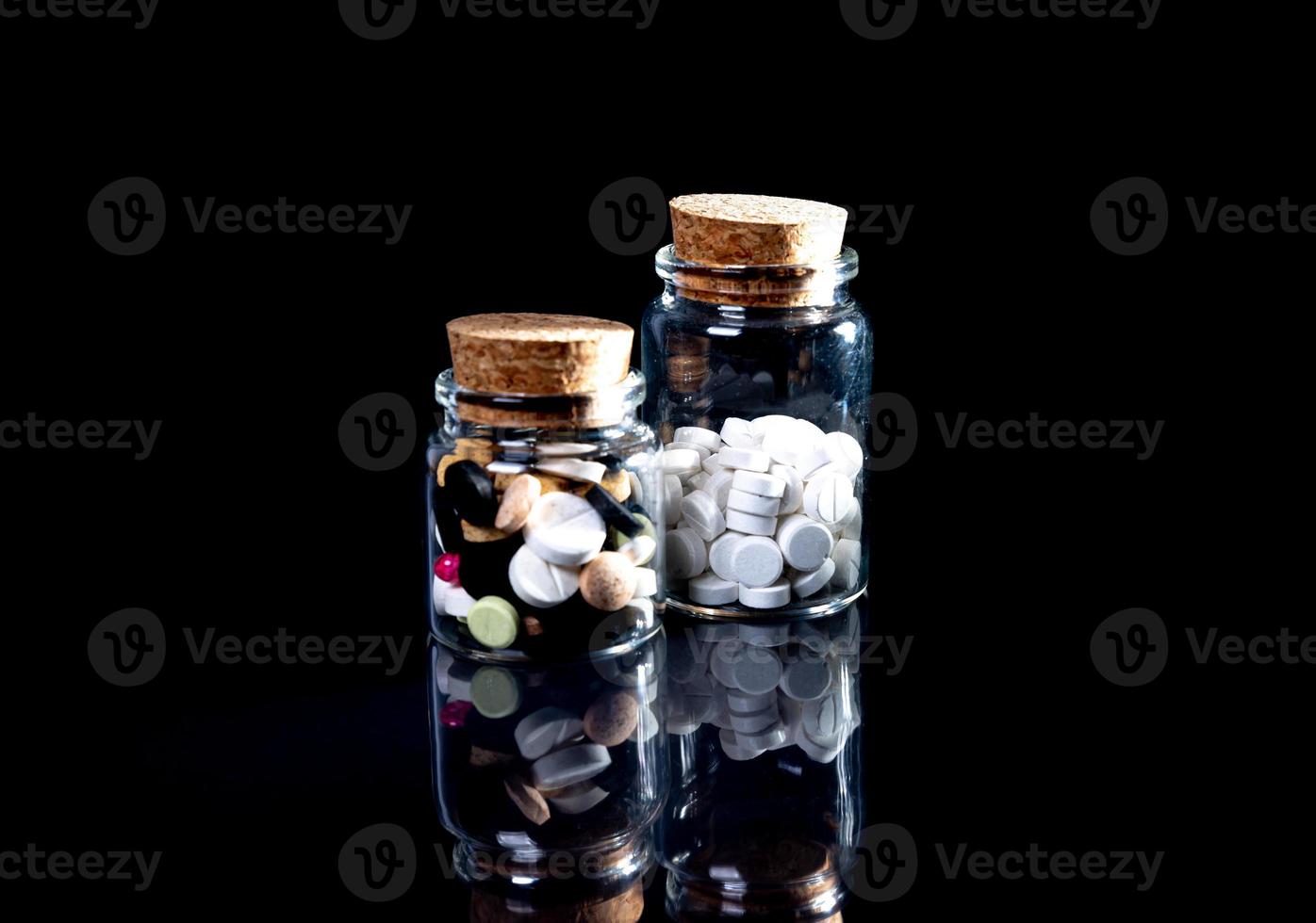 white orange pills in wineglass glass . in jar. in bucket Isolated on black set of capsule and pills inside closeup, photo