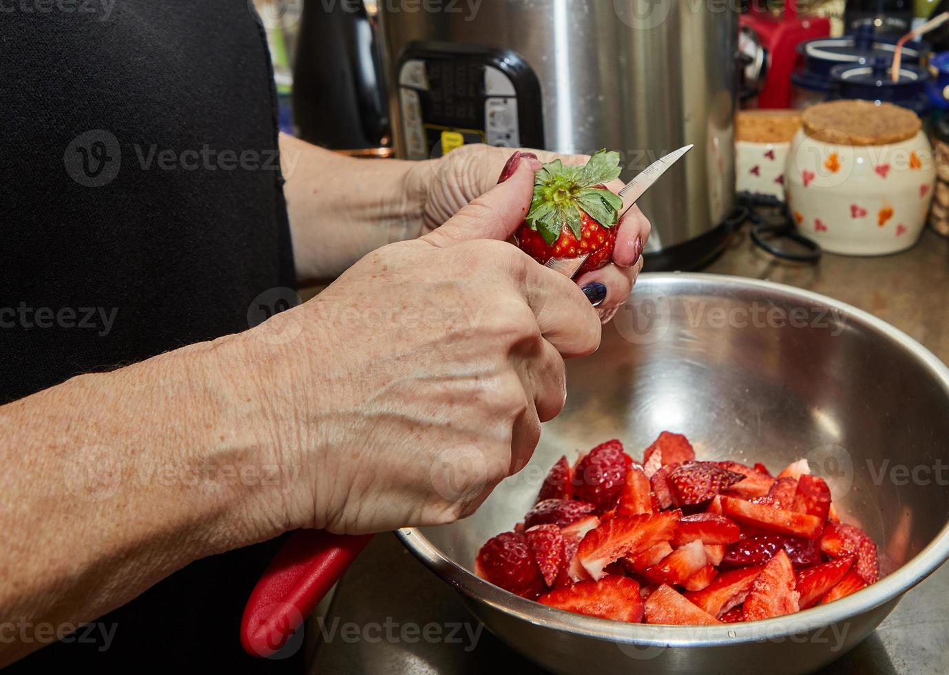 Chef cuts strawberries for dessert in the home kitchen photo