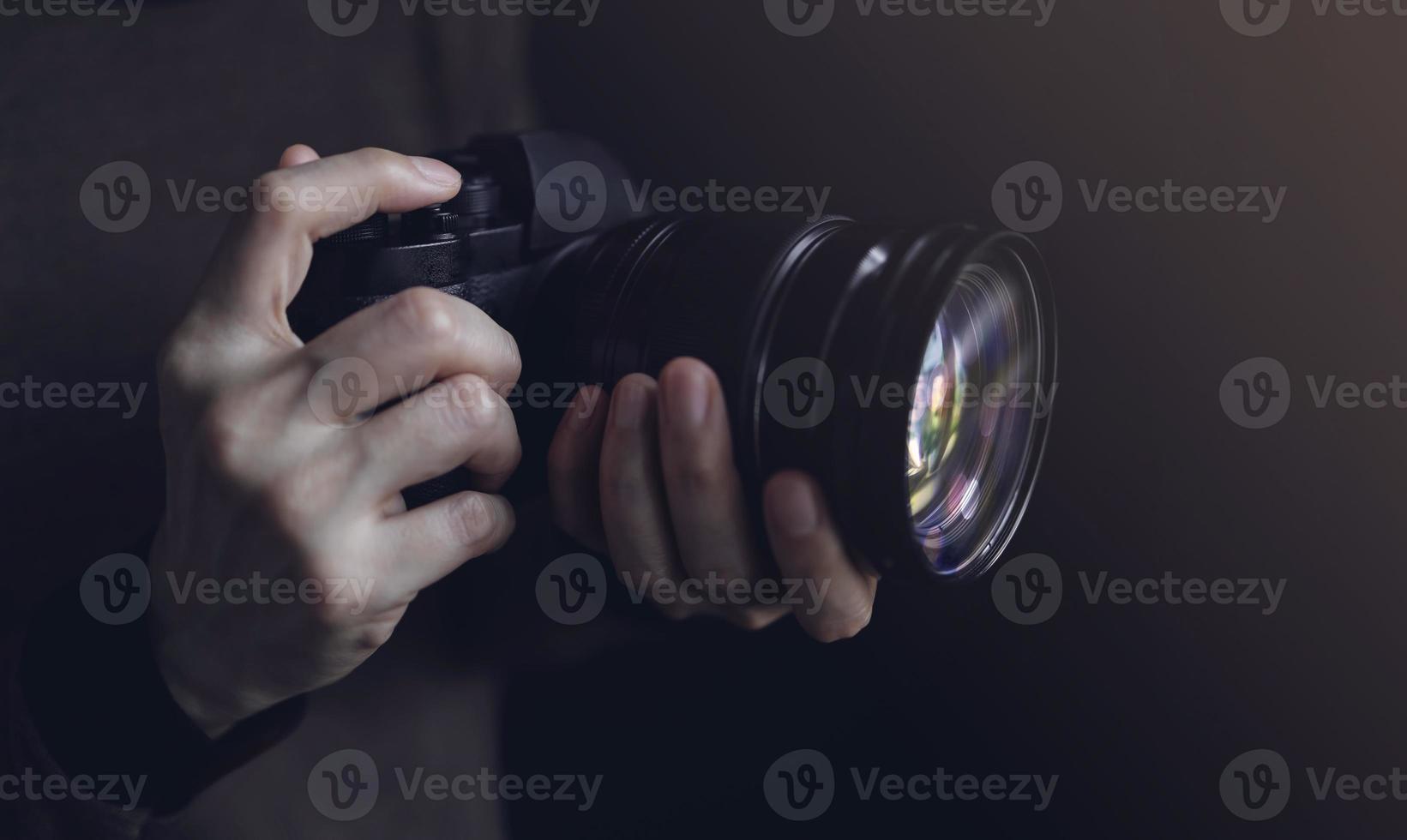 Young Photographer Woman using Camera to Taking Photo. Dark Tone. Selective Focus on Hand photo