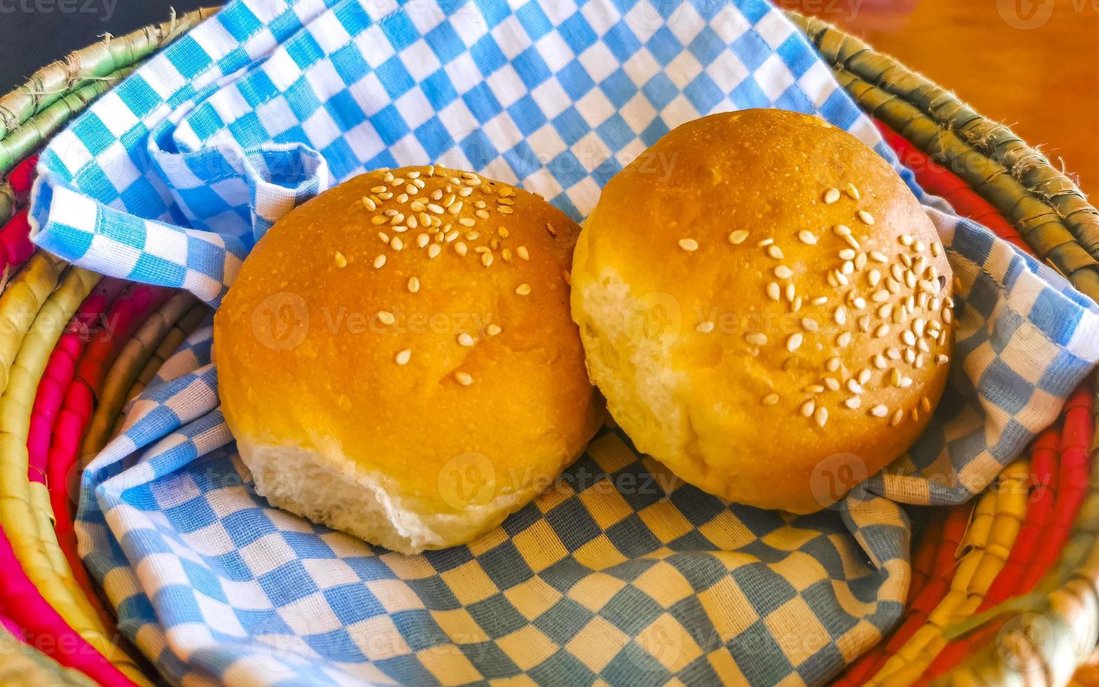 Delicious round buns with sesame seeds on wooden table Mexico. photo