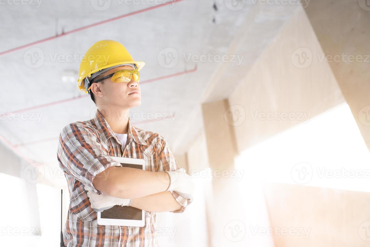 Worker and focused architect or engineer working on construction site using digital tablet. Mature man working on digital tablet at construction site. Mid adult manual worker checking list on laptop. photo