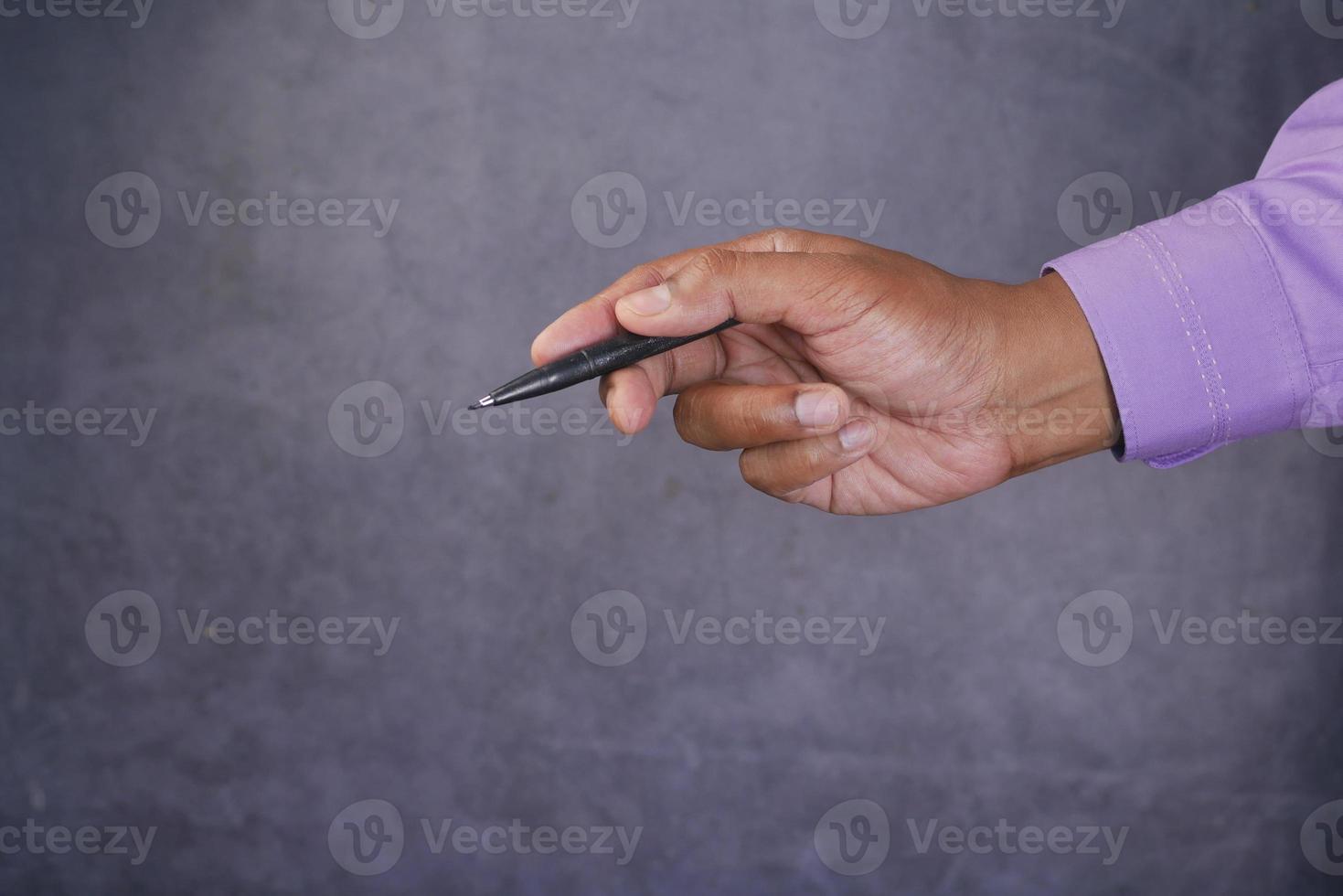 side view of holding a pen pointing something against black background photo