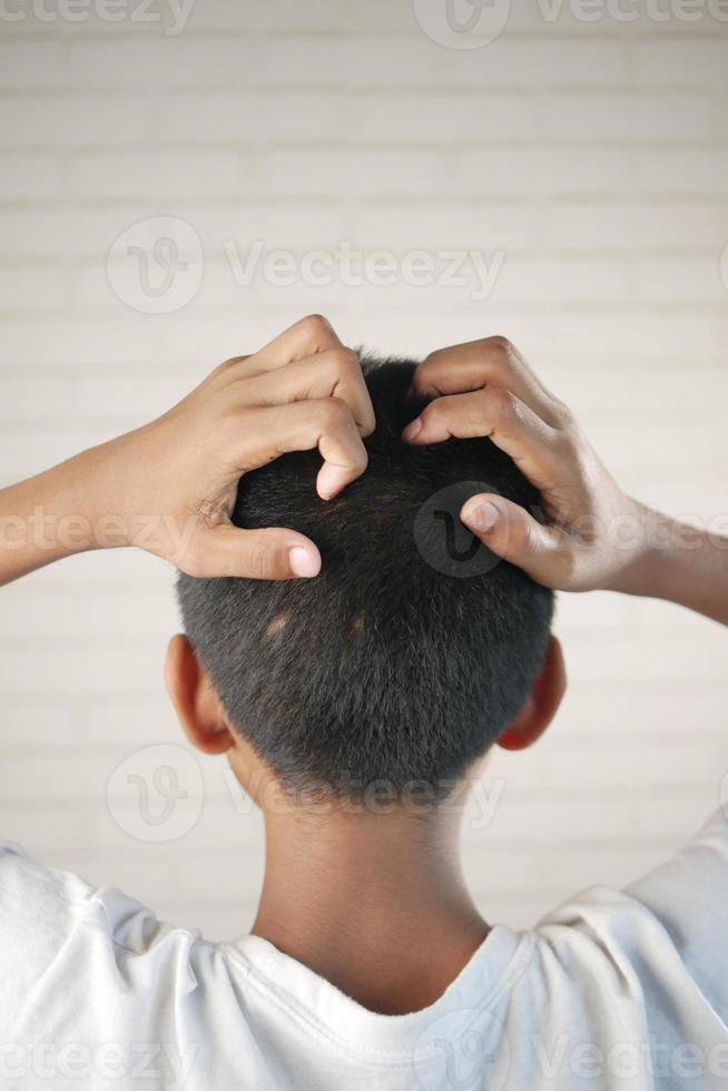 teenage boy Scratching Head Against black background . photo