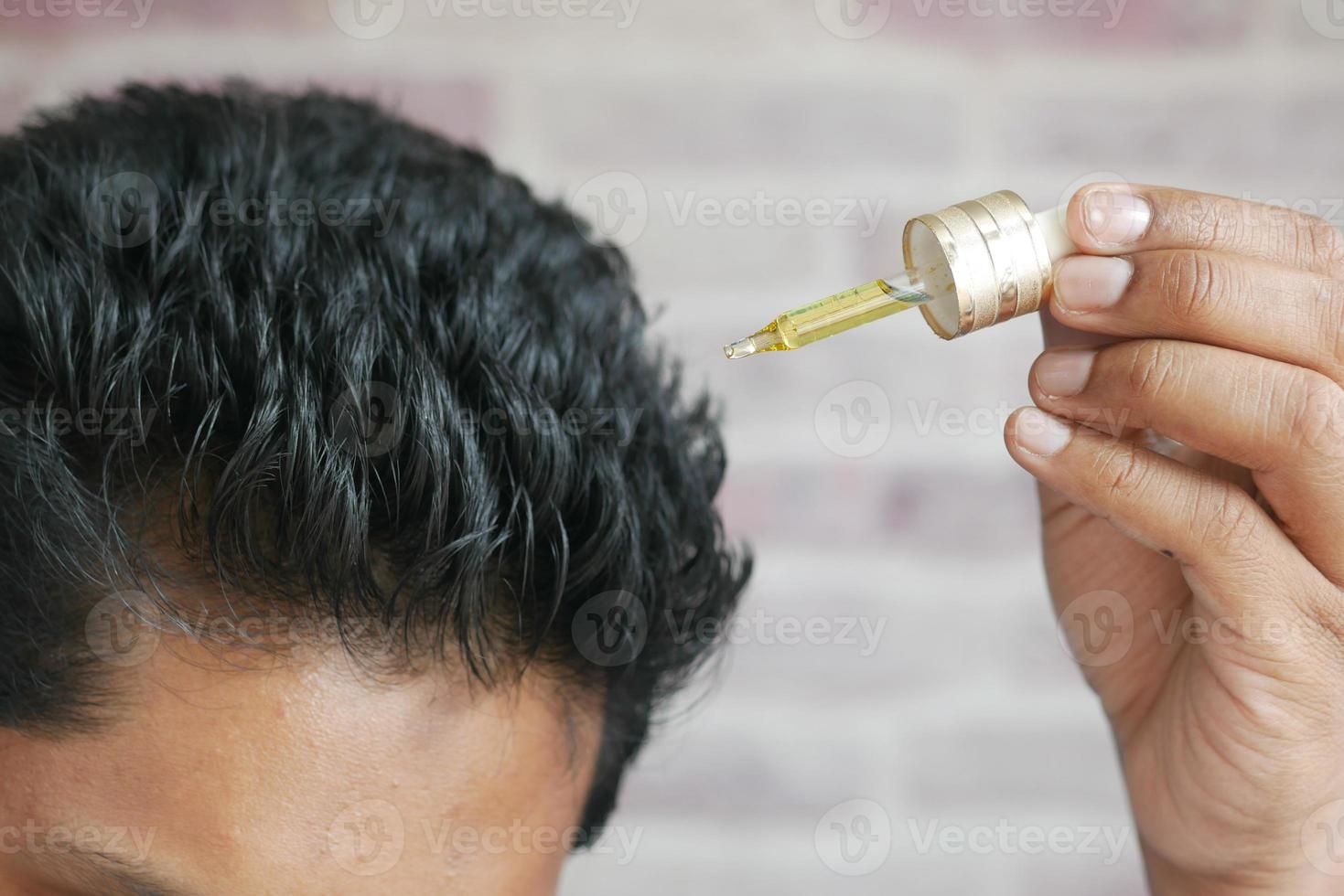 young men applying essential oils on his hair photo