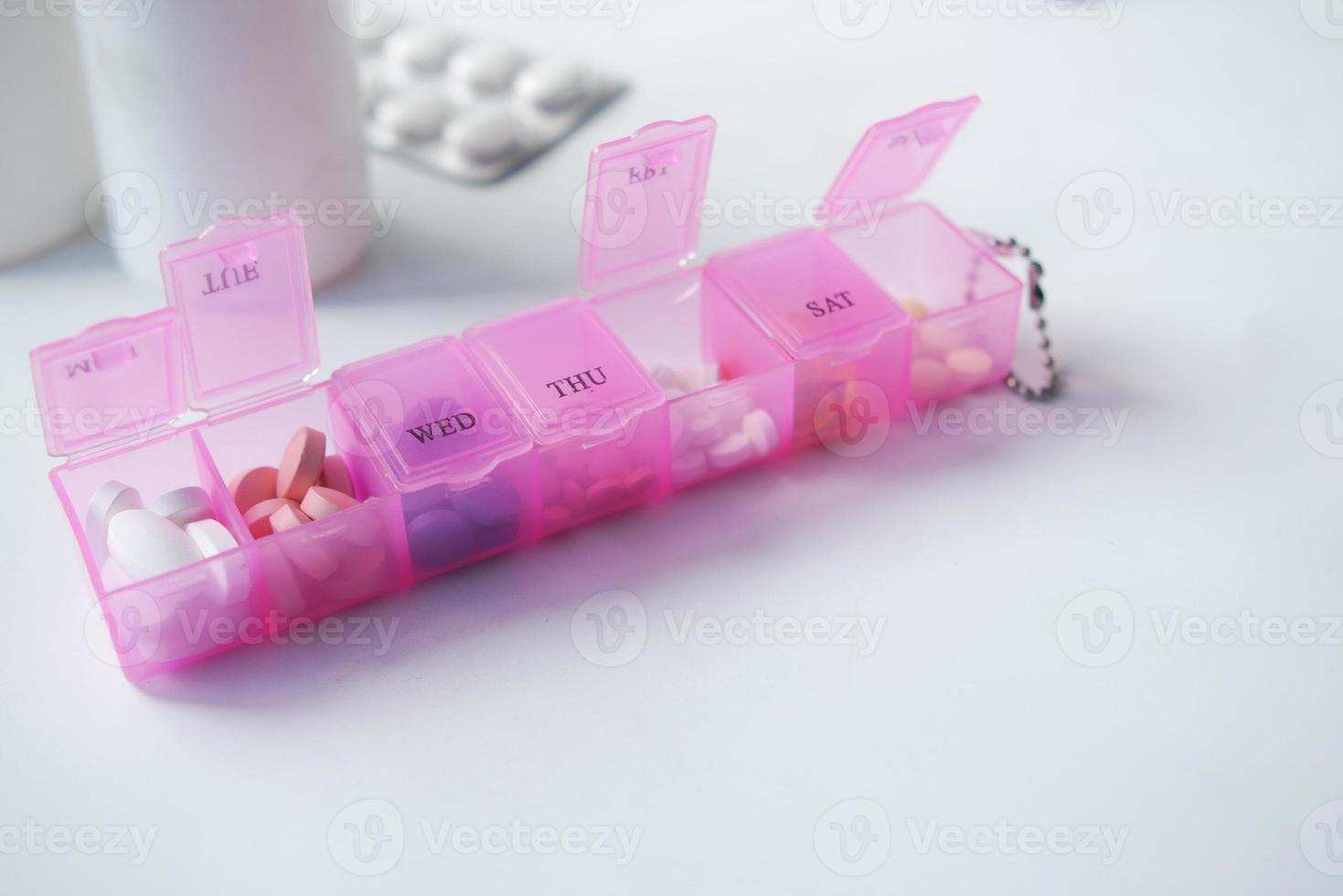 medical pills in a pink color pill box on table photo