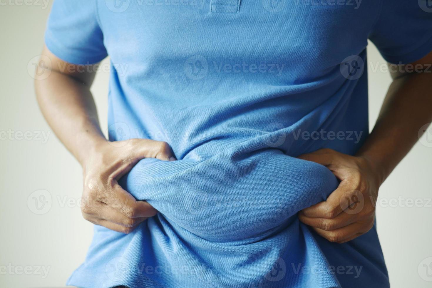 man's hand holding excessive belly fat, overweight concept photo