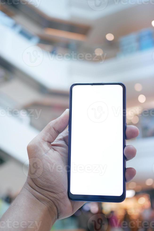 young man hand using smart phone with green screen against city buildings photo