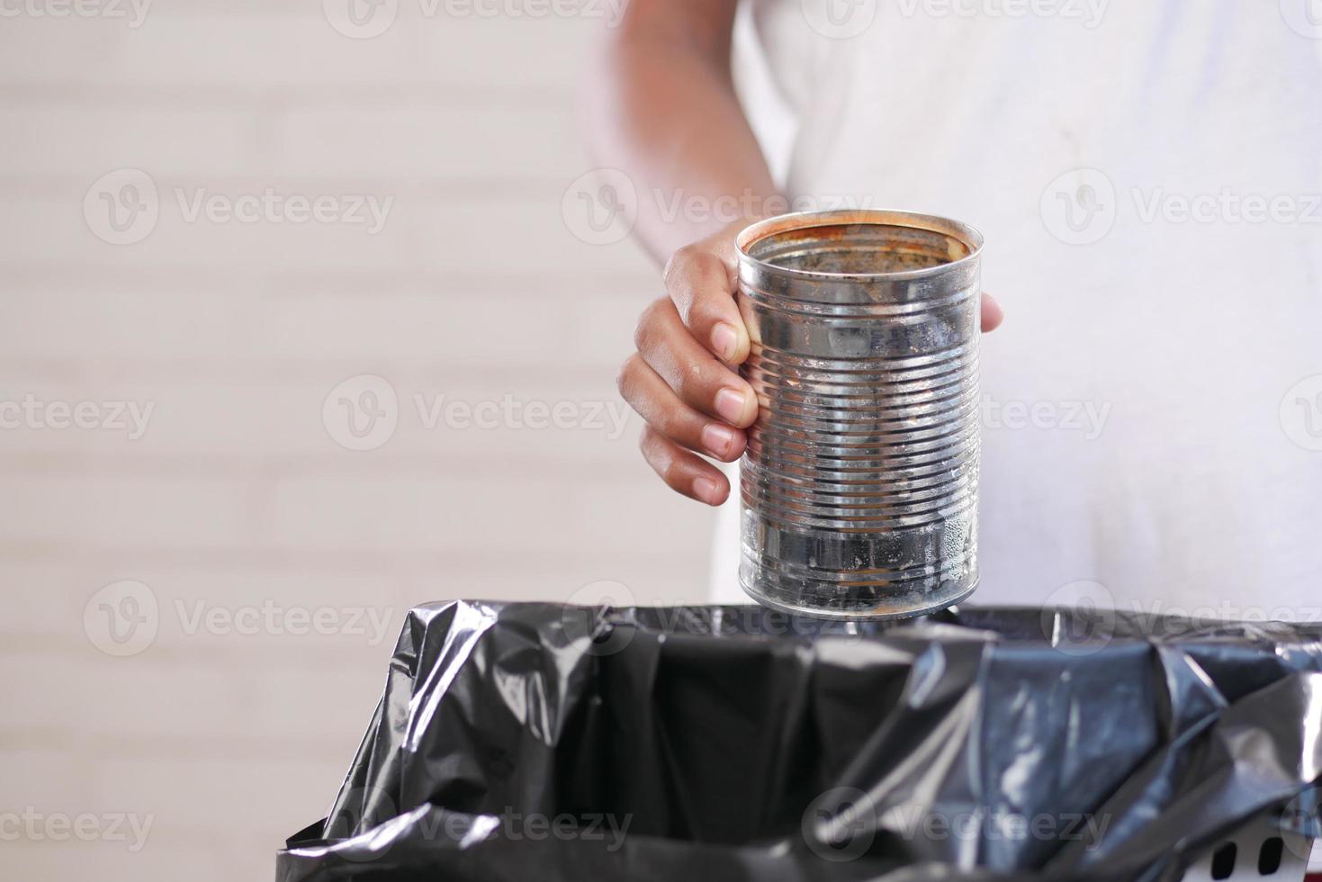 tirar un recipiente de hojalata en un basurero foto