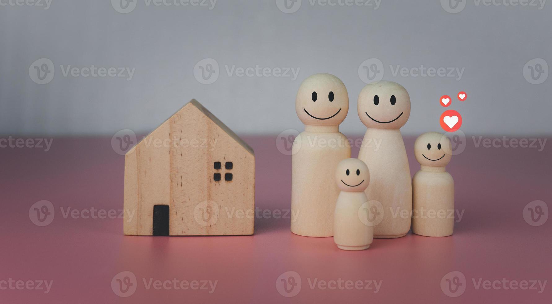 Happy house concept. Model house with wooden dolls standing lined up on pink background and heart icons. Indicates happiness and love in the home. photo