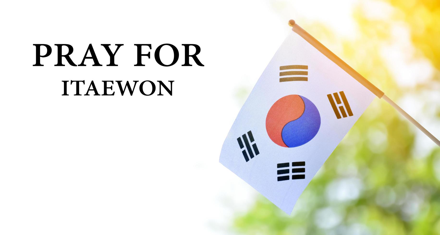 Korea National flag with blurred background and texts 'Pray for Itaewon', concept for showing a mourning for the many who died from falling on top of each other and suffocating in Itaewon city. photo