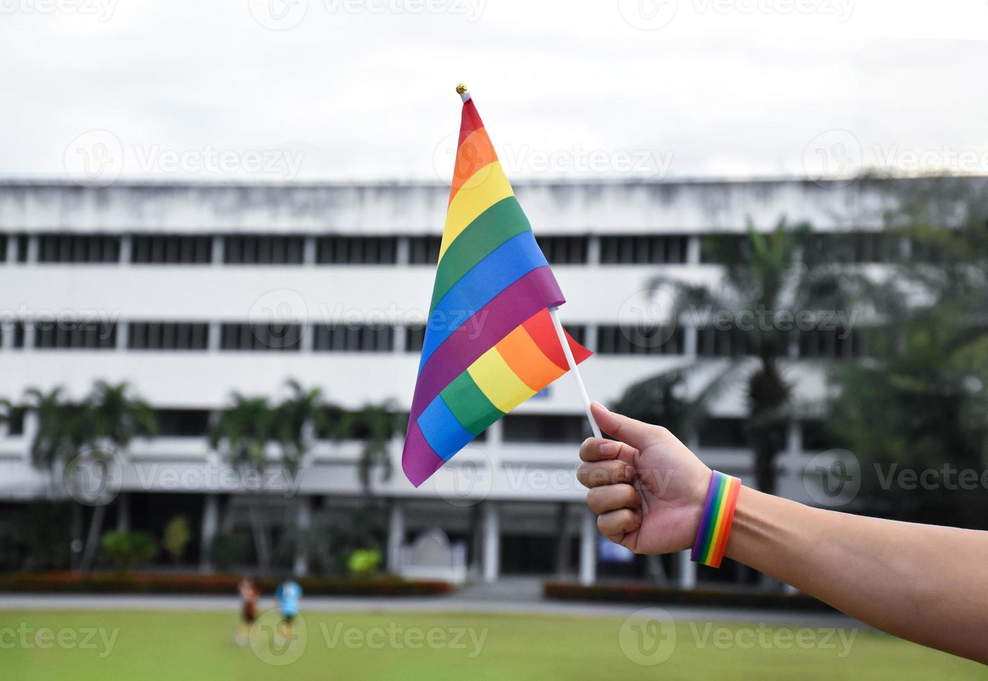 Rainbow flag holing in hand of asian gay which wears rainbow wristband to call out and shows LGBT gender diversity and respecting gender alternative around the world. photo