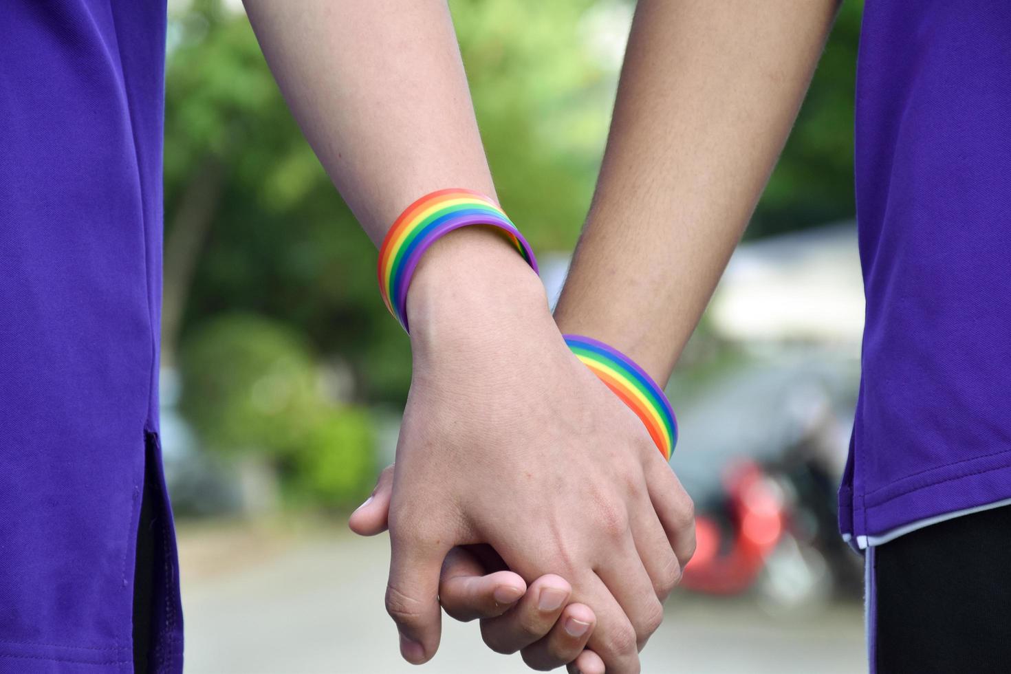 Rainbow wristband wearing in hand of young asian gay to show and represent gender diversity, to respect human rights in alternative sex, to stop punishing homosexuals in some religions photo