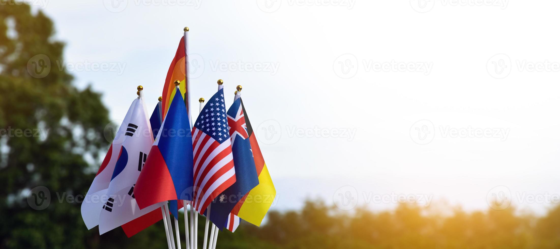 banderas del arco iris y banderas de muchos países frente al césped verde de la escuela asiática, concepto para la celebración de los géneros lgbtq en el mes del orgullo en todo el mundo, enfoque suave y selectivo. foto