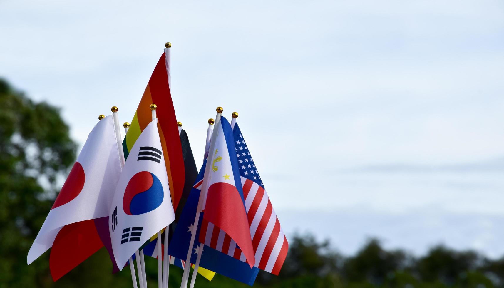 Rainbow flags and flags of many countries with clouds and bluesky background, concept for celebration of lgbtq genders in pride month around the world, soft and selective focus. photo