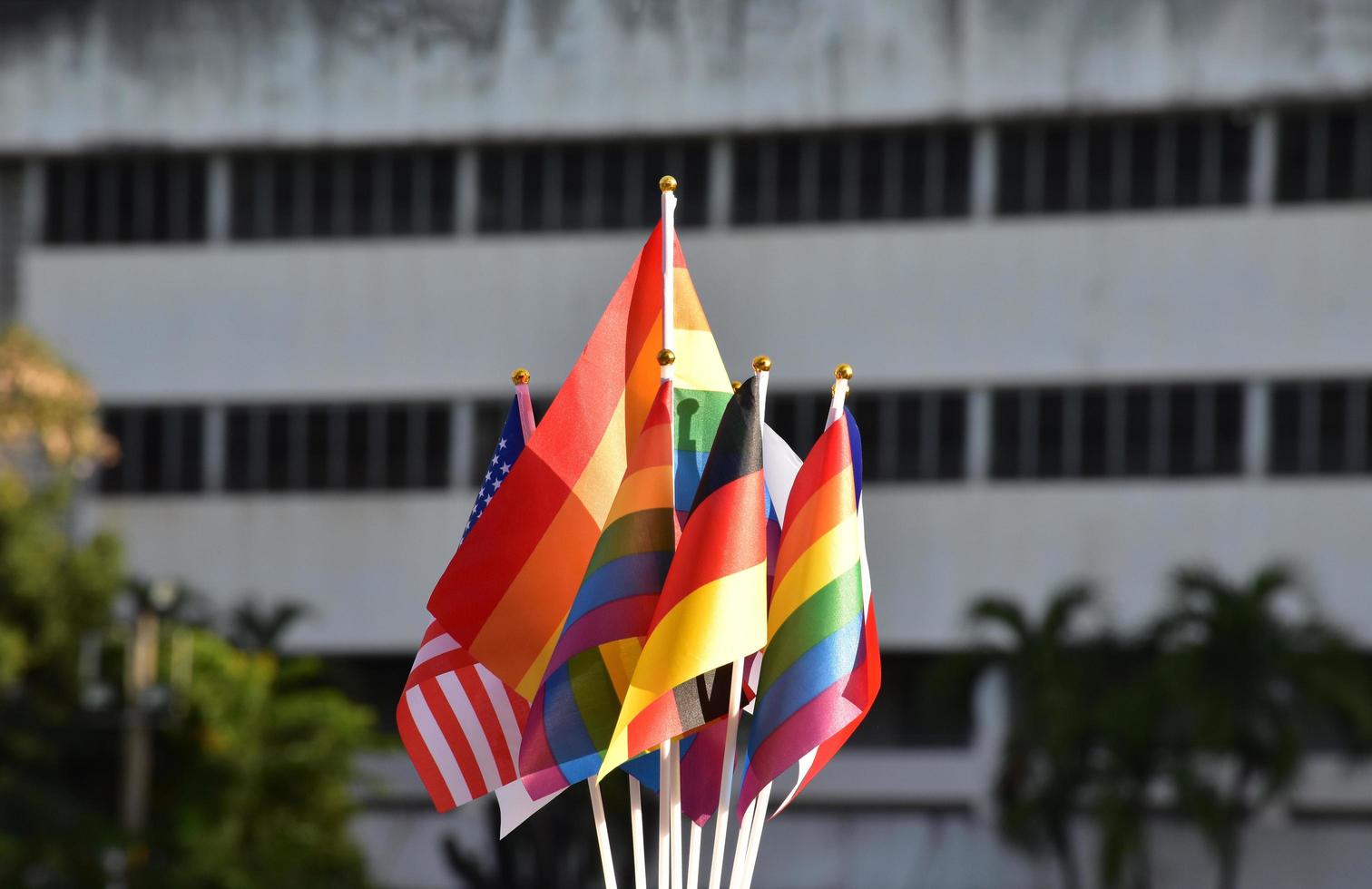 banderas del arco iris y banderas de muchos países frente al gran edificio de la escuela asiática, concepto para la celebración de lgbtq más géneros en el mes del orgullo en todo el mundo, enfoque suave y selectivo. foto