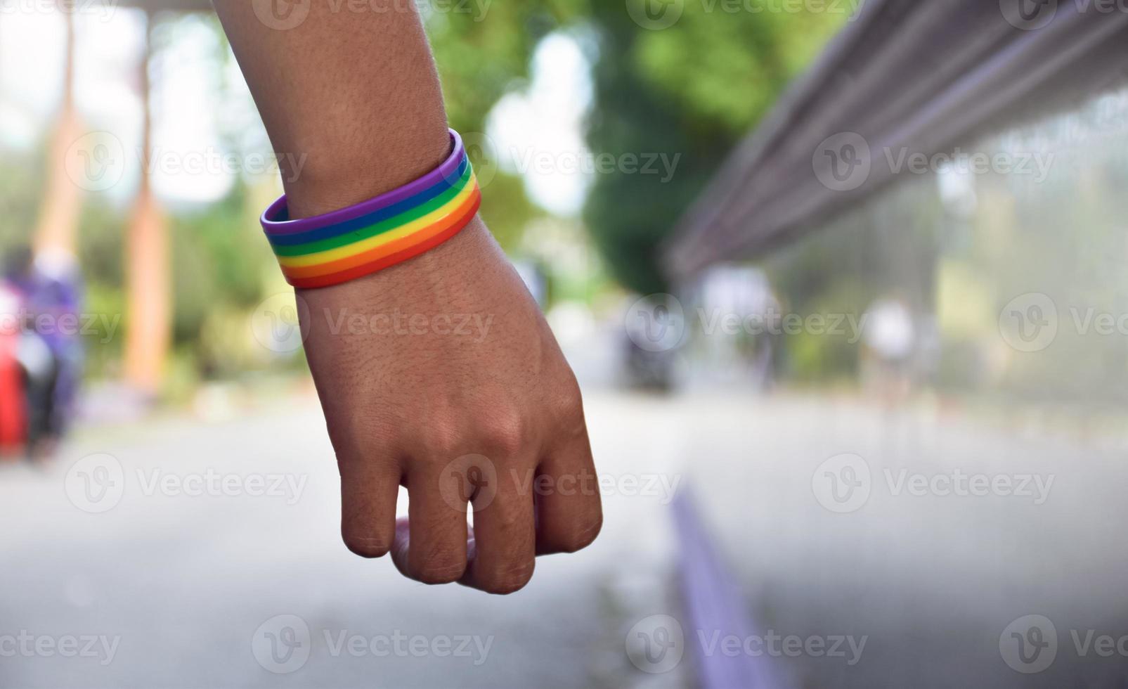 Rainbow wristband wearing in hand of young asian gay to show and represent gender diversity, to respect human rights in alternative sex, to stop punishing homosexuals in some religions photo