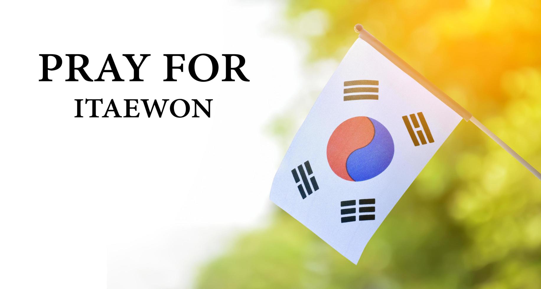 Korea National flag with blurred background and texts 'Pray for Itaewon', concept for showing a mourning for the many who died from falling on top of each other and suffocating in Itaewon city. photo
