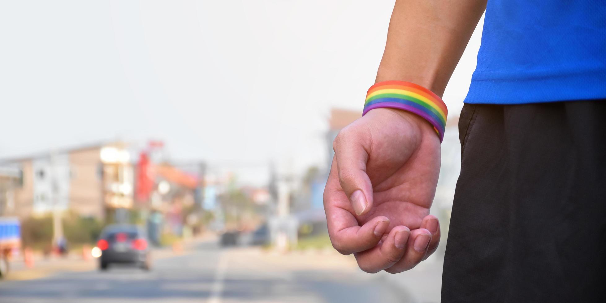 Rainbow wristband wearing in hand of young asian gay to show and represent gender diversity, to respect human rights in alternative sex, to stop punishing homosexuals in some religions. photo