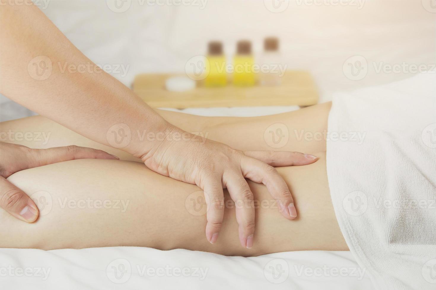 la mano del masajista masajea los músculos de la pantorrilla de la mujer joven en el salón de spa. concepto de salud, relajación o uso de productos naturales para cuidar la piel de las piernas foto