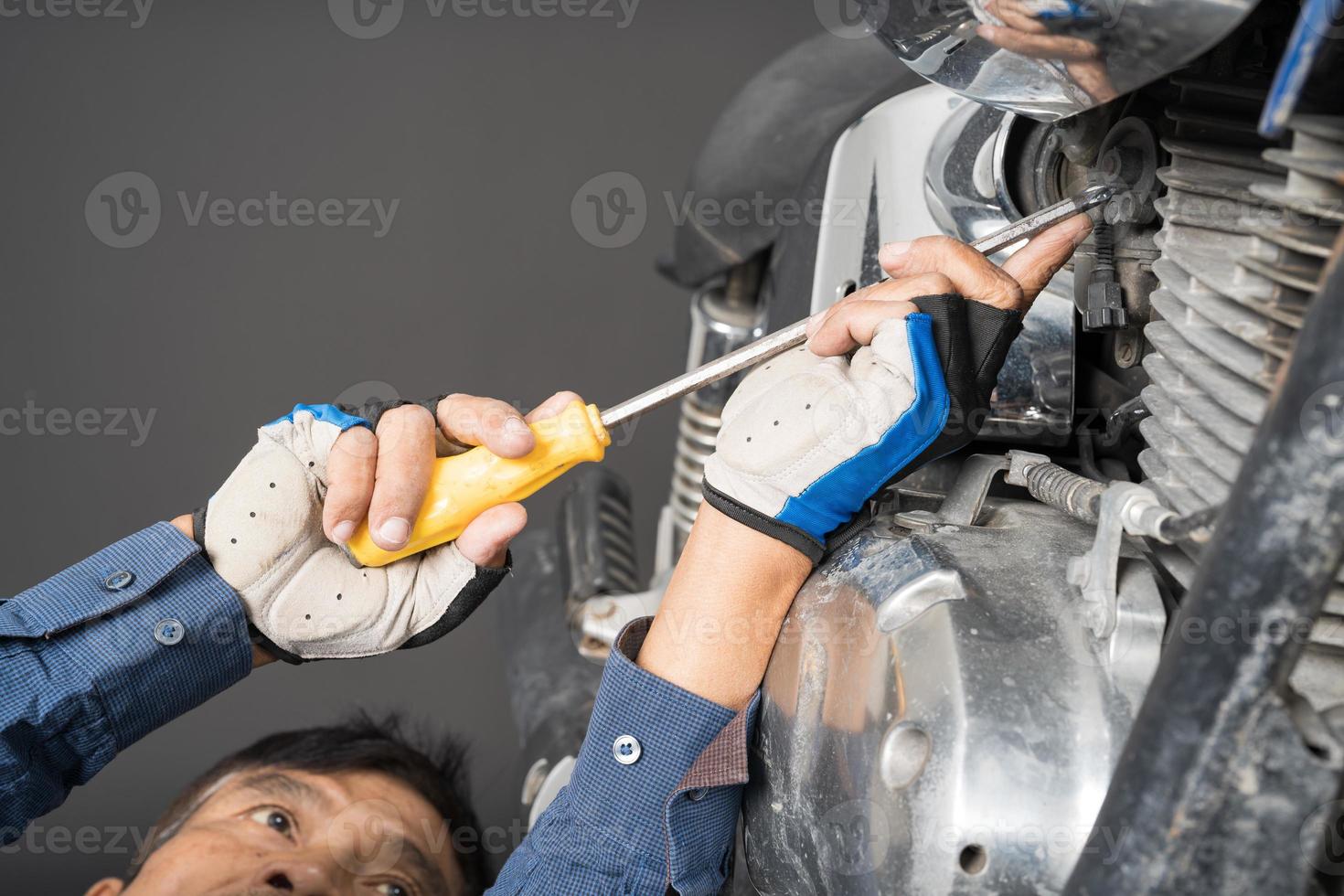People are repairing a motorcycle Use a wrench and a screwdriver to work photo