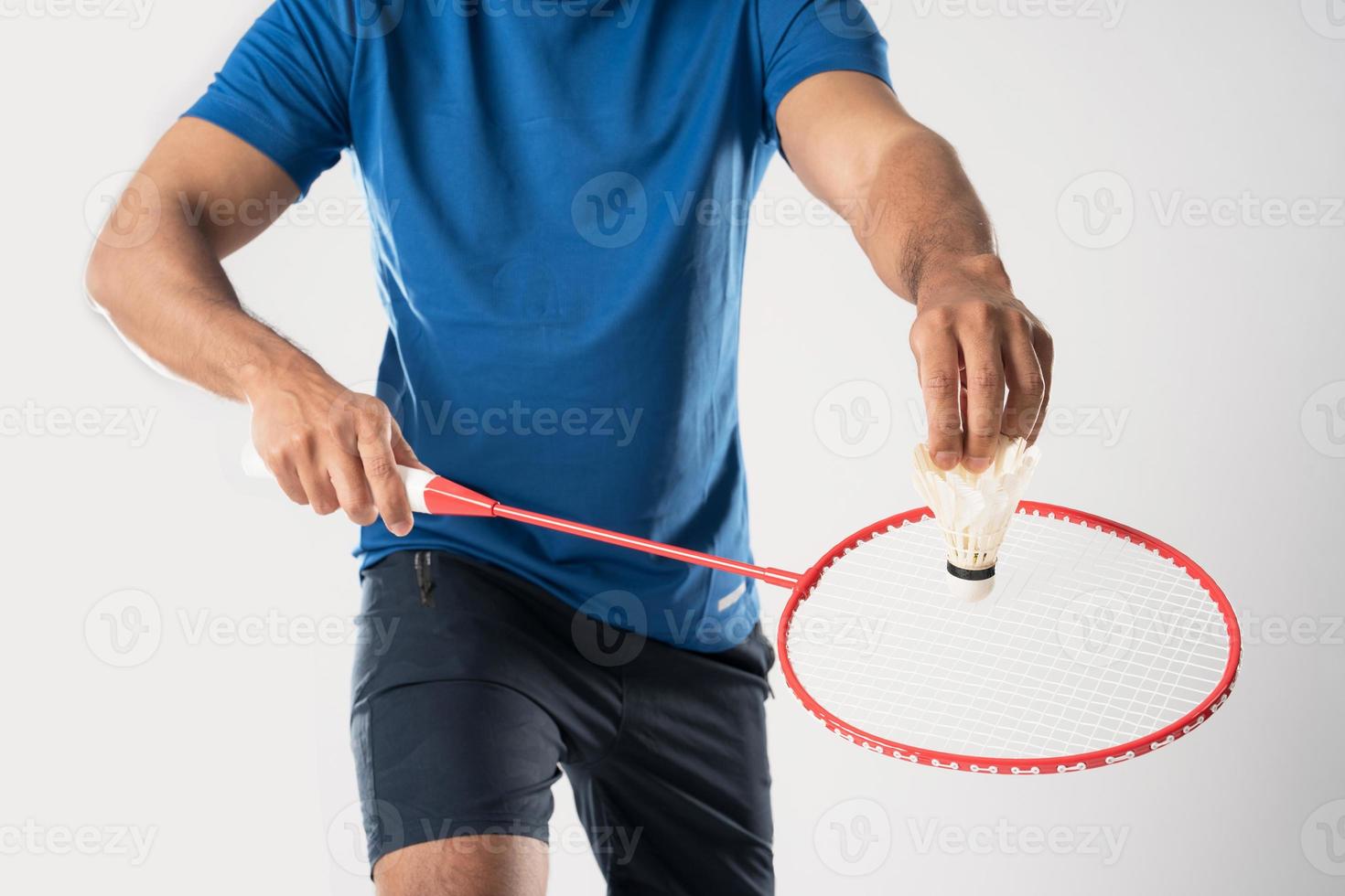A badminton player in sportswear stands holding a racket and shuttlecock. photo