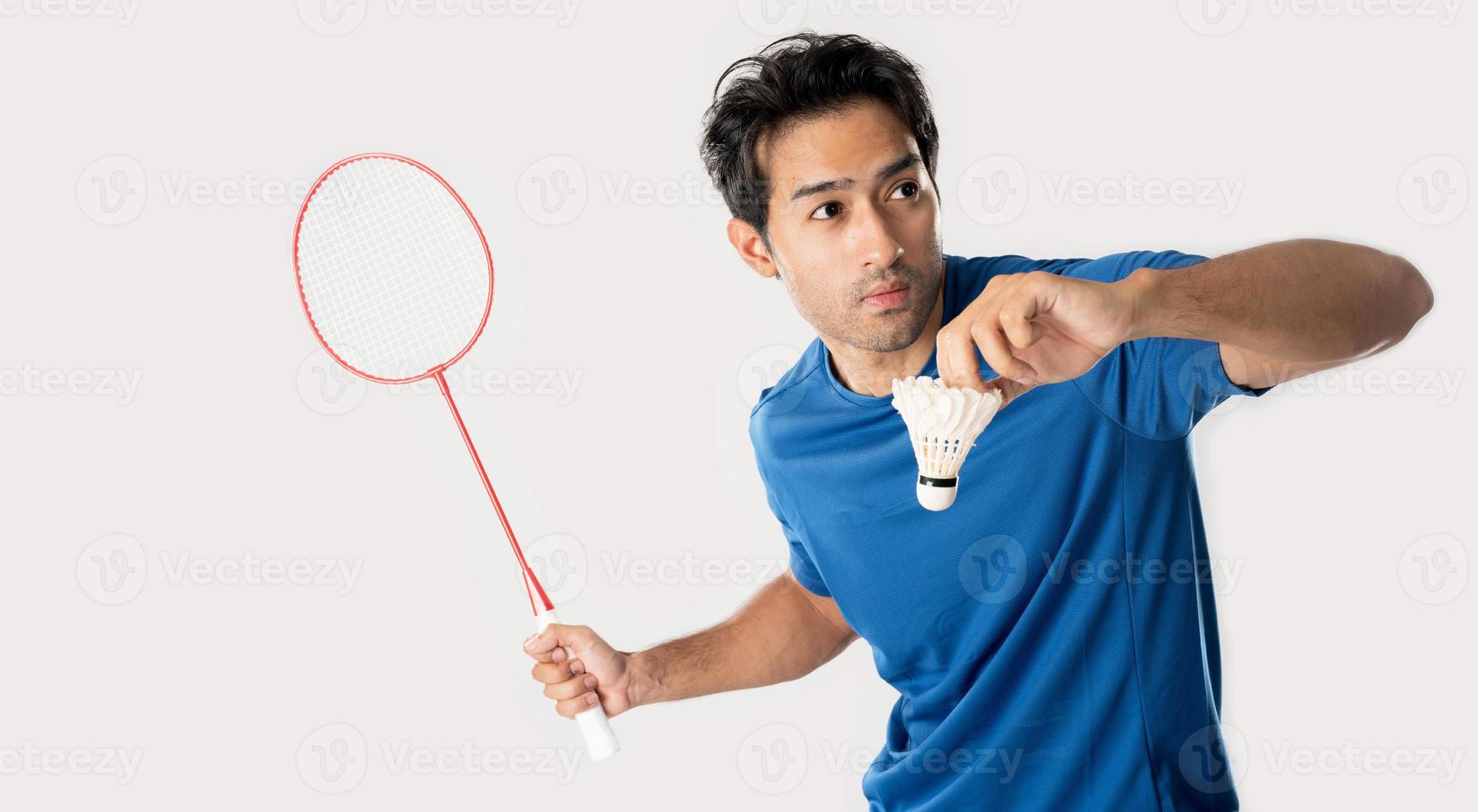 A badminton player in sportswear stands holding a racket and shuttlecock. photo