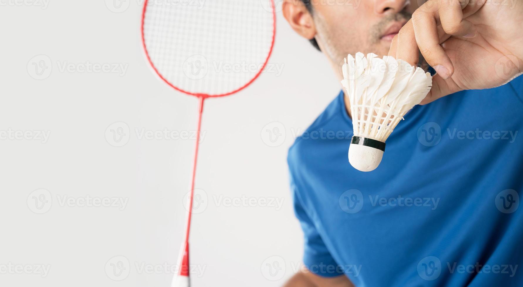 A badminton player in sportswear stands holding a racket and shuttlecock. photo