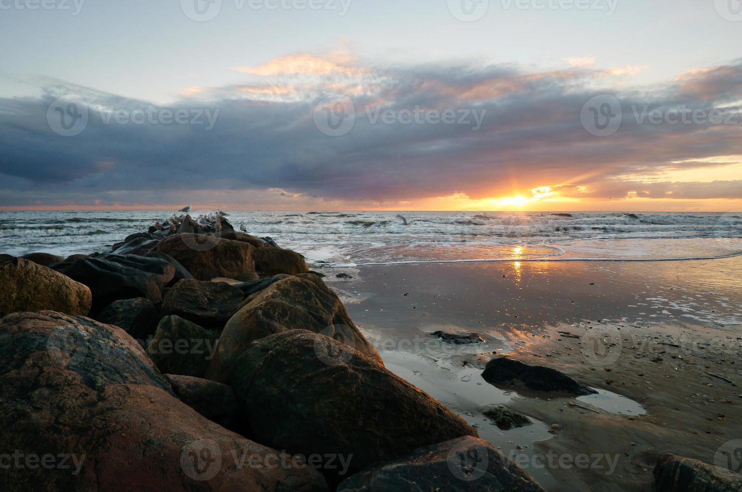 Sunset on the beach in Denmark. Stone groyne in the foreground. Walk on the coast photo