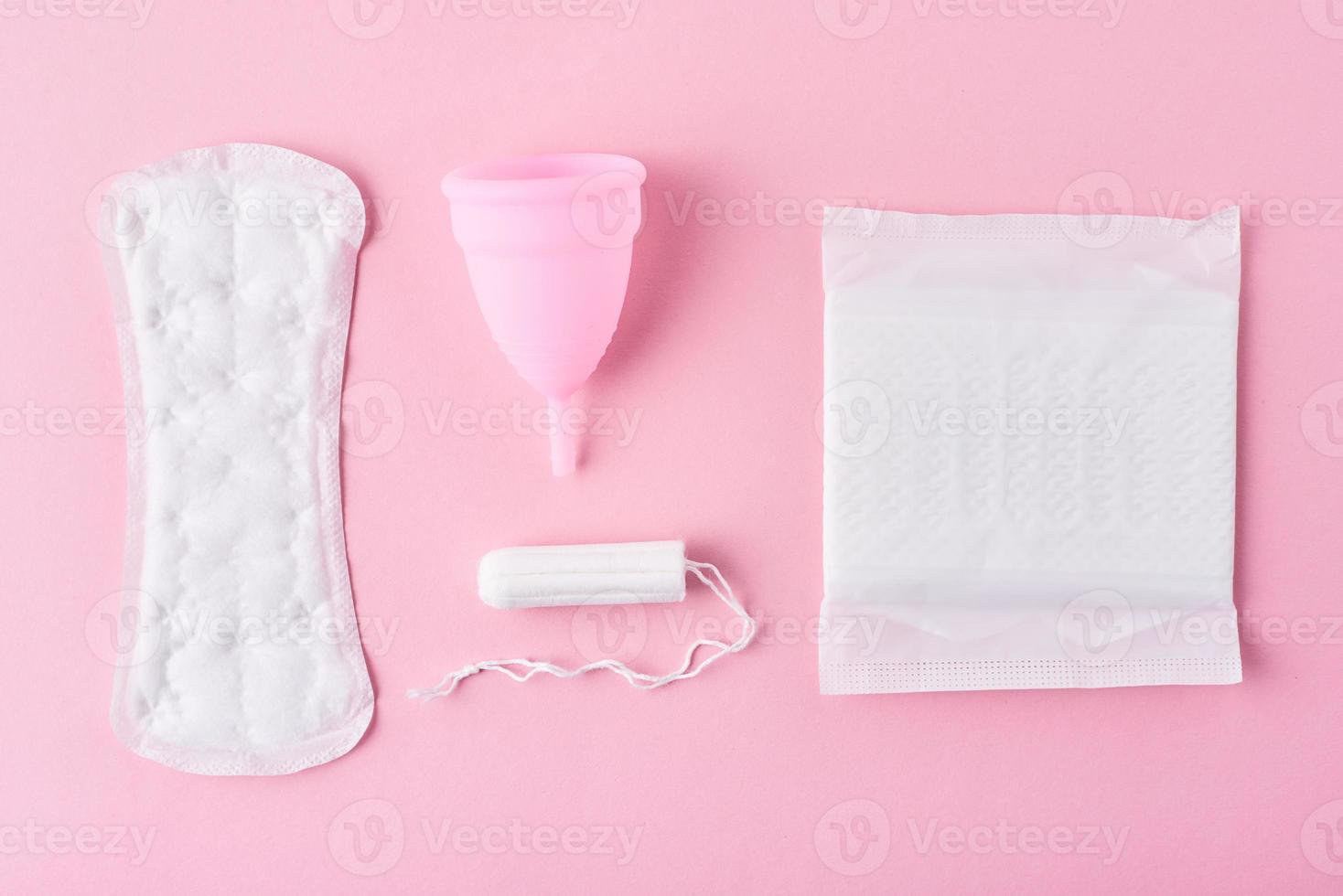 toalla sanitaria, copa menstrual y tampón sobre un fondo rosa, vista superior foto