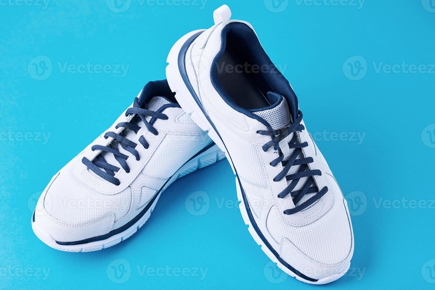 Pair of male white sneakers on a blue background. Sport shoe close up photo